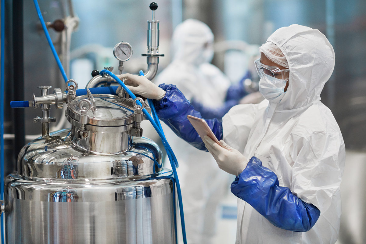 Portrait of female worker wearing protective suit while operating equipment at modern chemical plant, copy space